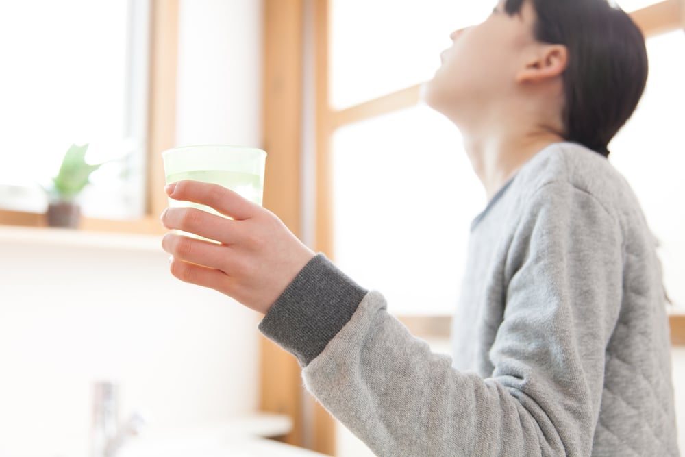 Girl gargles with salt water as an at-home oral hygiene routine