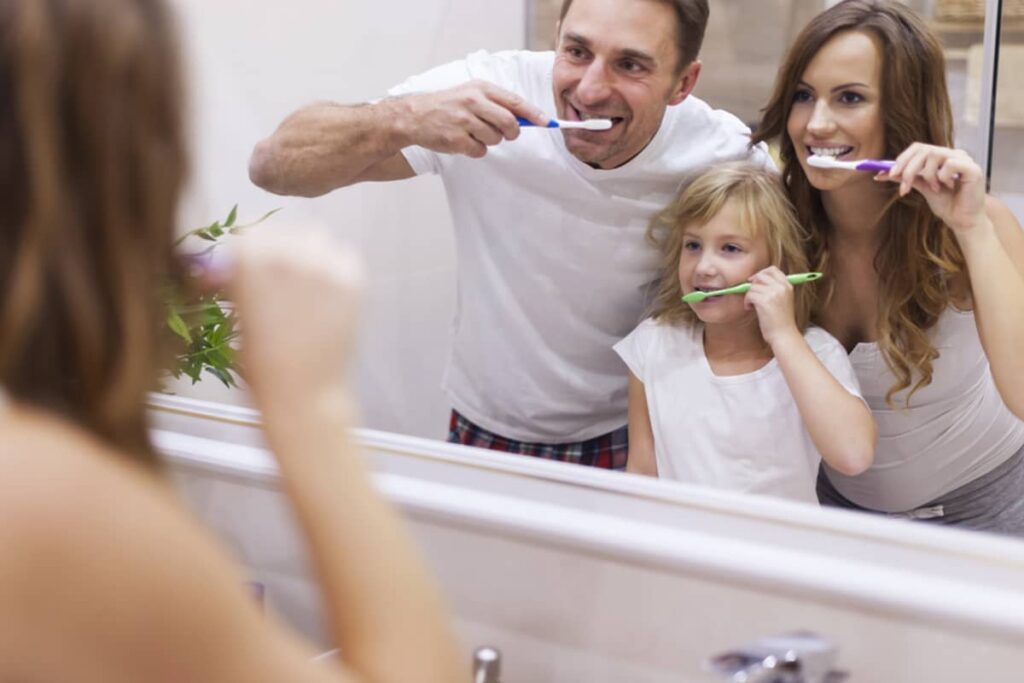 Parents teaching their young daughter how to brush
