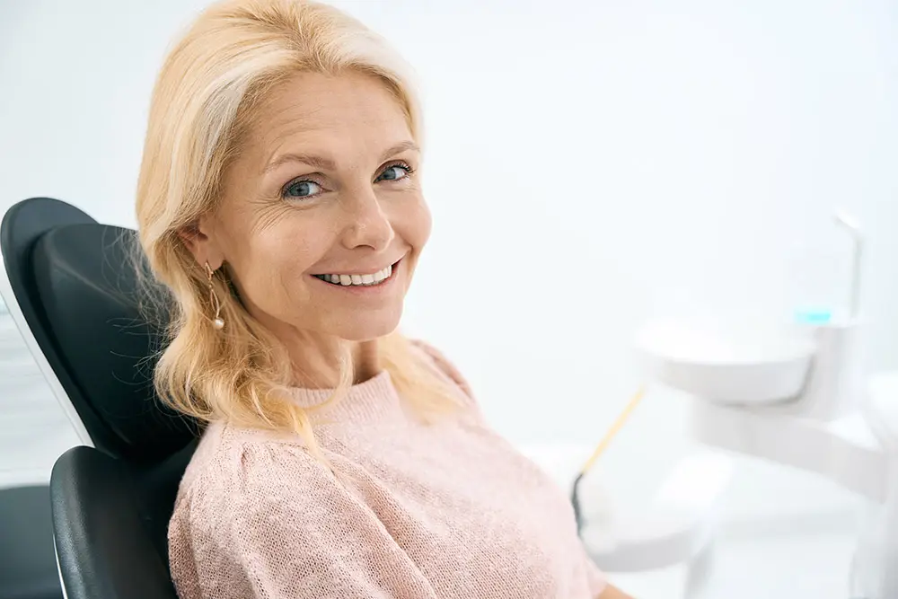 Happy patient with a beautiful and natural-looking smile thanks to an experienced professional dentist who performed a permanent bridge procedure.