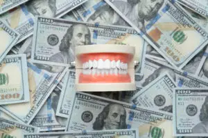 Dollar bills with a full set of teeth on them to represent dental medical procedures or gum tissue graft costs.