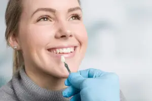 Happy patient in a dental appointment preparing for a dental crown procedure with the dentist presenting temporary crowns.