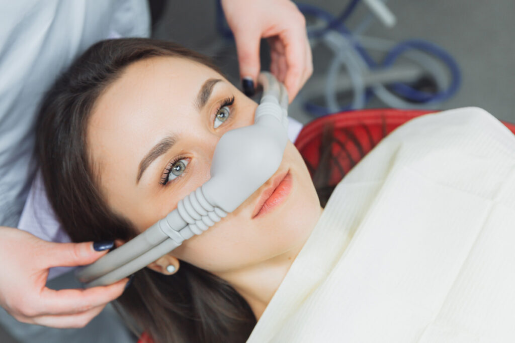 Woman with nitrous oxide mask in dental clinic, highlighting sedation efficiency.