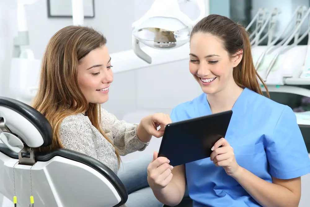 Patient and dental professional discussing treatment options on a tablet in a modern dental office.