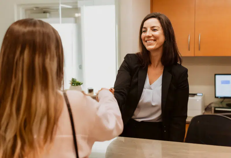 Friendly dental office receptionist greeting patient while discussing payment and financing options in Miami clinic.