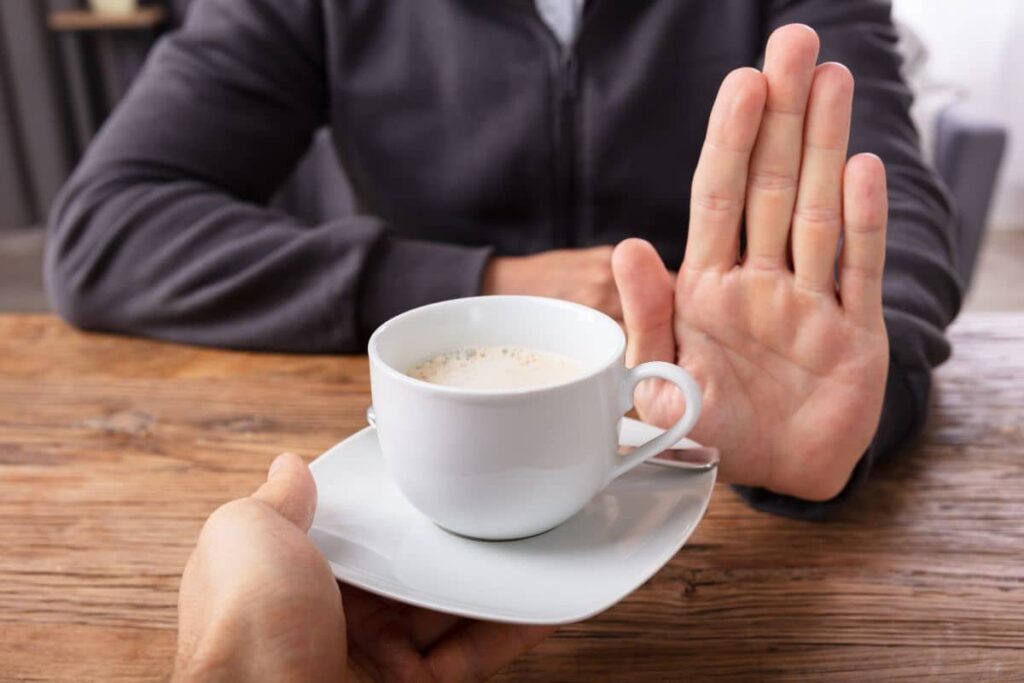 Person refusing a cup of coffee, illustrating post-LANAP surgery guideline to avoid hot beverages for healing.