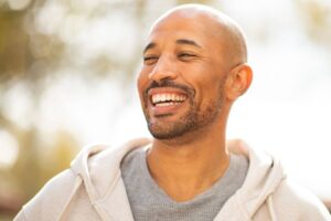 Smiling man representing confidence after choosing dental implants or bridge tooth replacement options