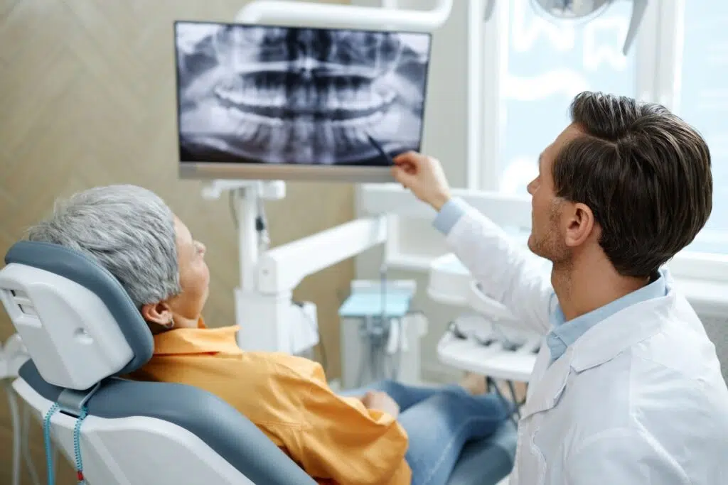 Dentist reviewing dental X-ray with patient during early periodontal disease treatment consultation