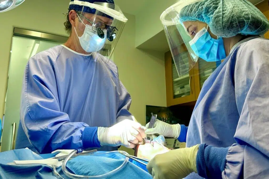 Dental team performing root canal treatment to remove infection and preserve a tooth affected by apical periodontitis.